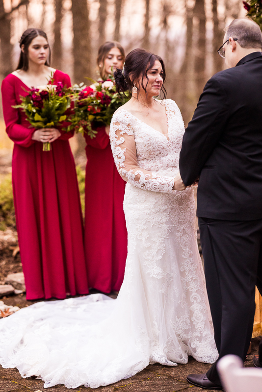 candid wedding photographer, lisa rhinehart, captures this authentic candid moment of the bride as she holds back tears during this romantic, cozy outdoor Christmas winter wedding ceremony at auradell at the stroudsmoor country inn 