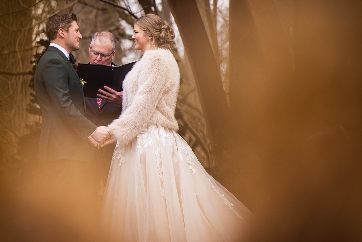 creative pa wedding photographer, Lisa Rhinehart, captures this unique, creative image of the bride and groom as they hold hands and share their vows during this outdoor Christmas wedding