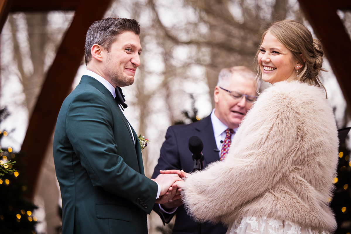 image of the bride and groom laughing as they share vows during this outdoor Christmas wedding 