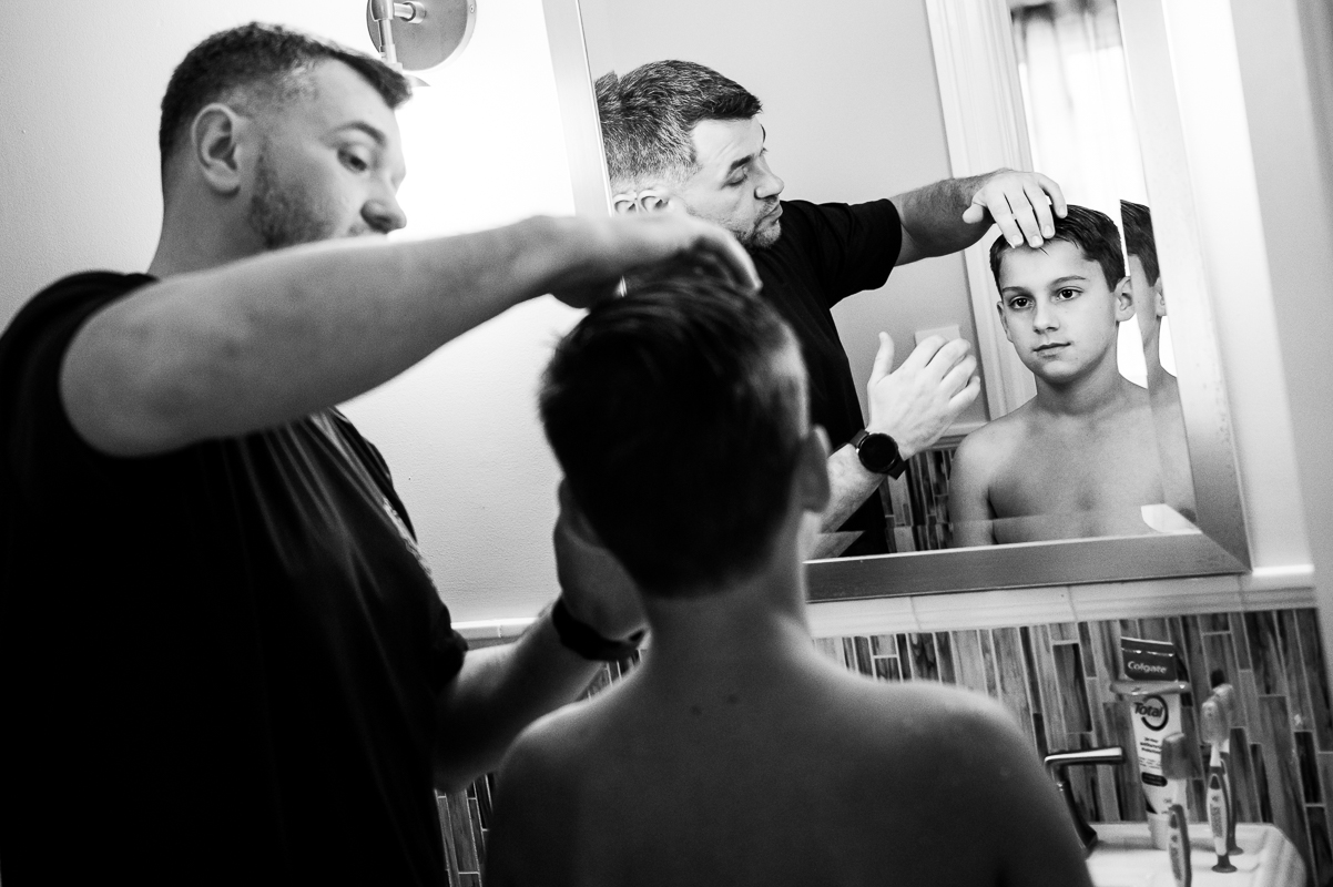 black and white image of the groom as he helps his son get ready before the wedding ceremony at the reeds at shelter haven 