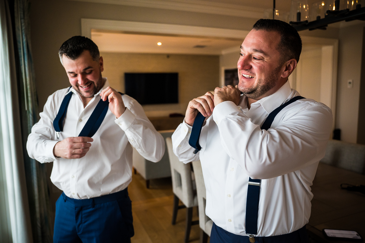 best pa wedding photographer, rhinehart photography, captures this fun preparation photo of the groom and his best man as they put their suspenders on the morning of this Christmas beach wedding