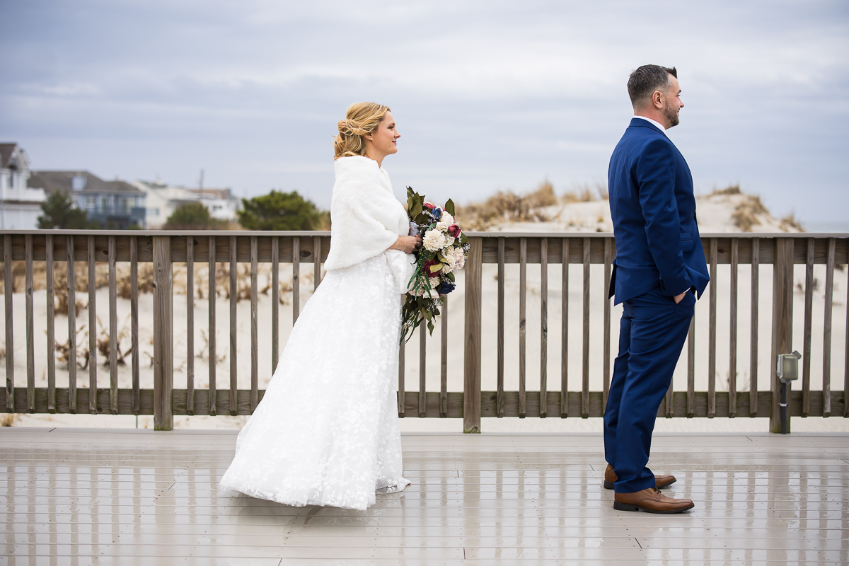 image of the bride and groom before they surprise one another at their first look on the beach during this Winter Reeds Stone Harbor Wedding