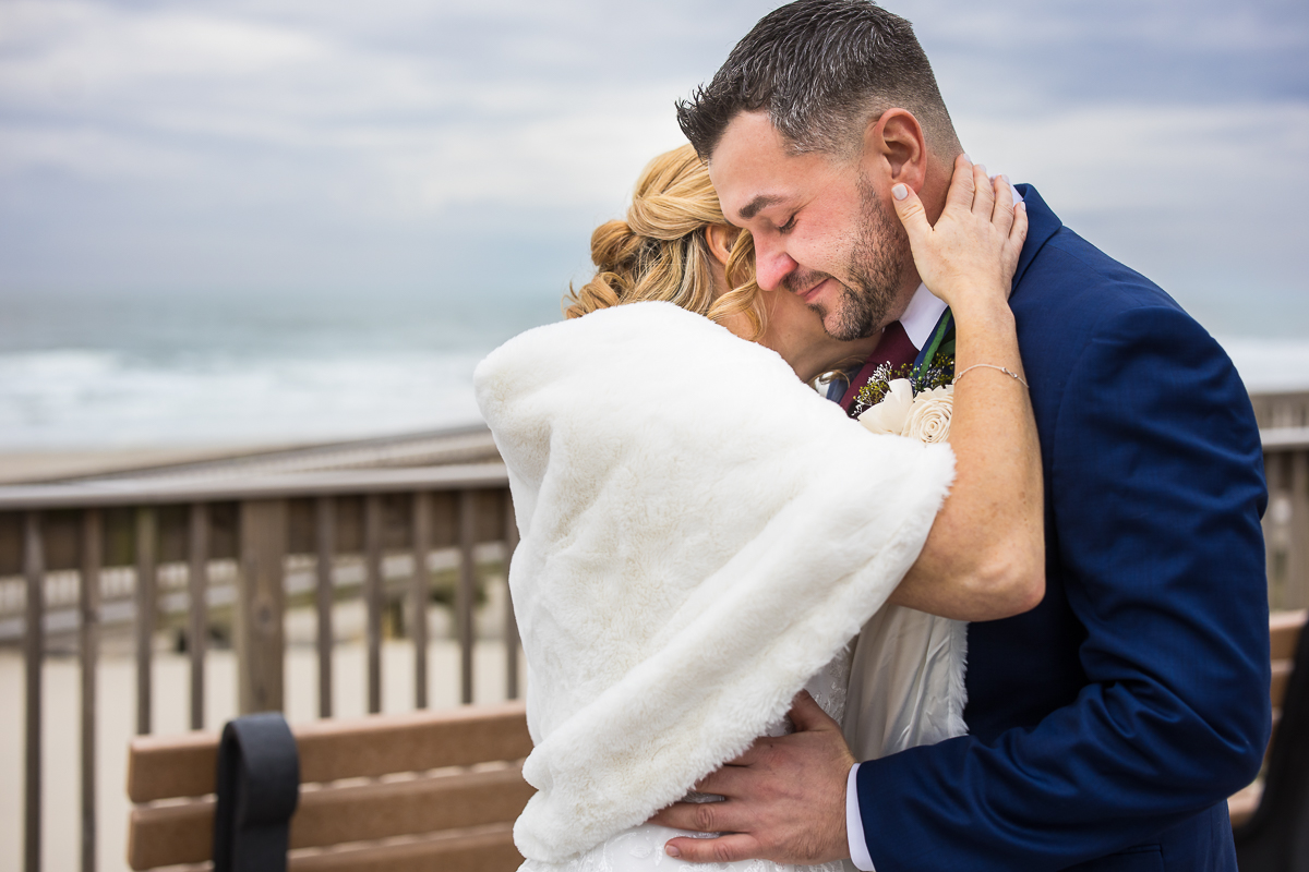 best nj wedding photographer, rhinehart photography, captures this emotional image of the bride and groom as they share a hug during their outdoor first look located on the beach at the reeds in stone harbor New Jersey 