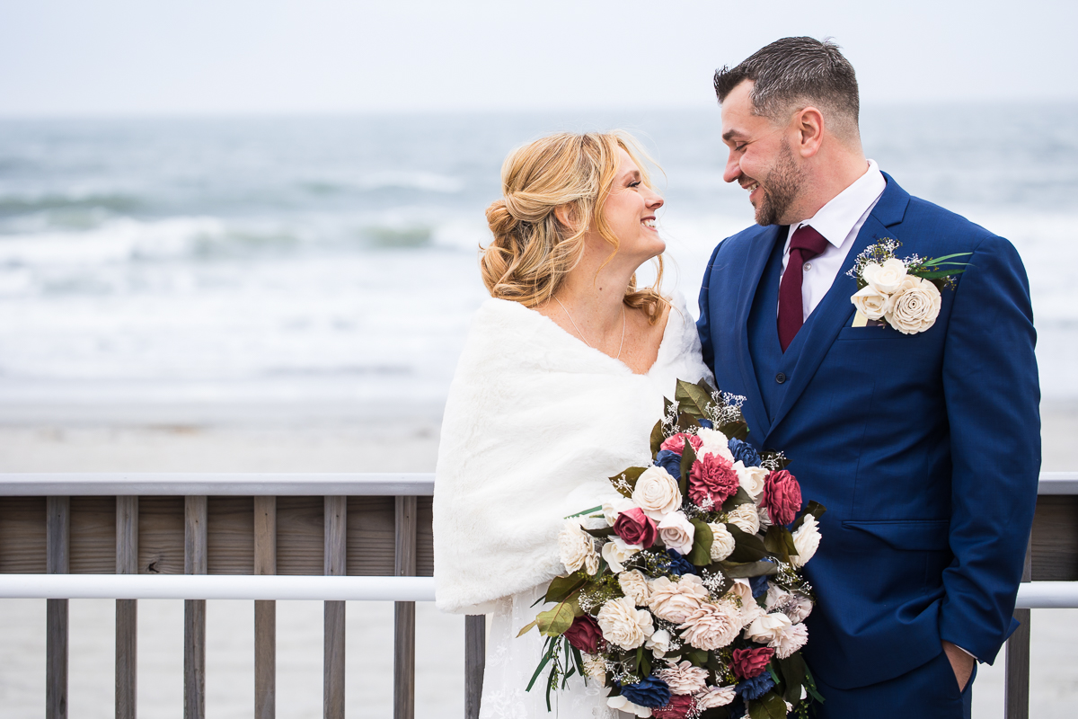 traditional portrait of the bride and groom as they stand by one another smiling after this outdoor first look on the beach located at the reeds in New Jersey 