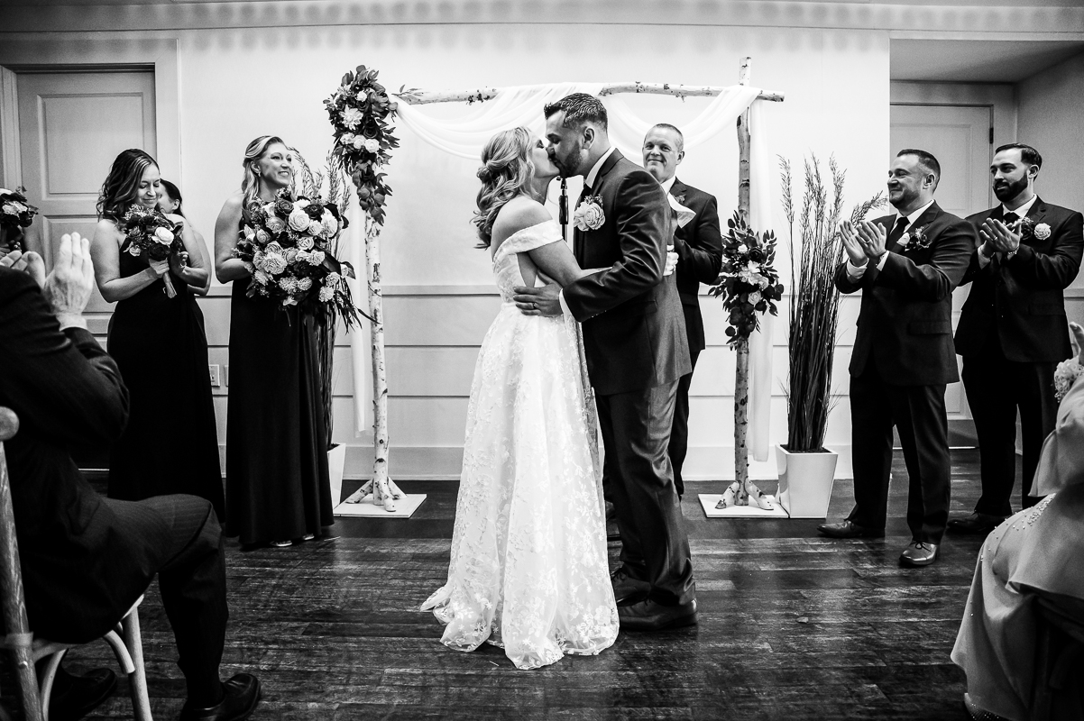 Winter Reeds Stone Harbor Wedding photographer, rhinehart photography, captures this black and white image of the bride and groom as they share their first kiss as a married couple during this winter wedding ceremony in New Jersey by the beach 