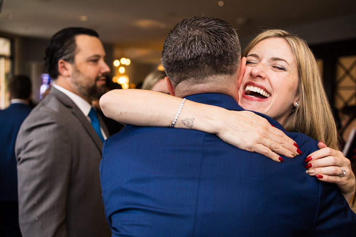 candid, fun image of guests as they hug the groom during cocktail hour aft this winter wedding ceremony at the reeds by the beach in stone harbor