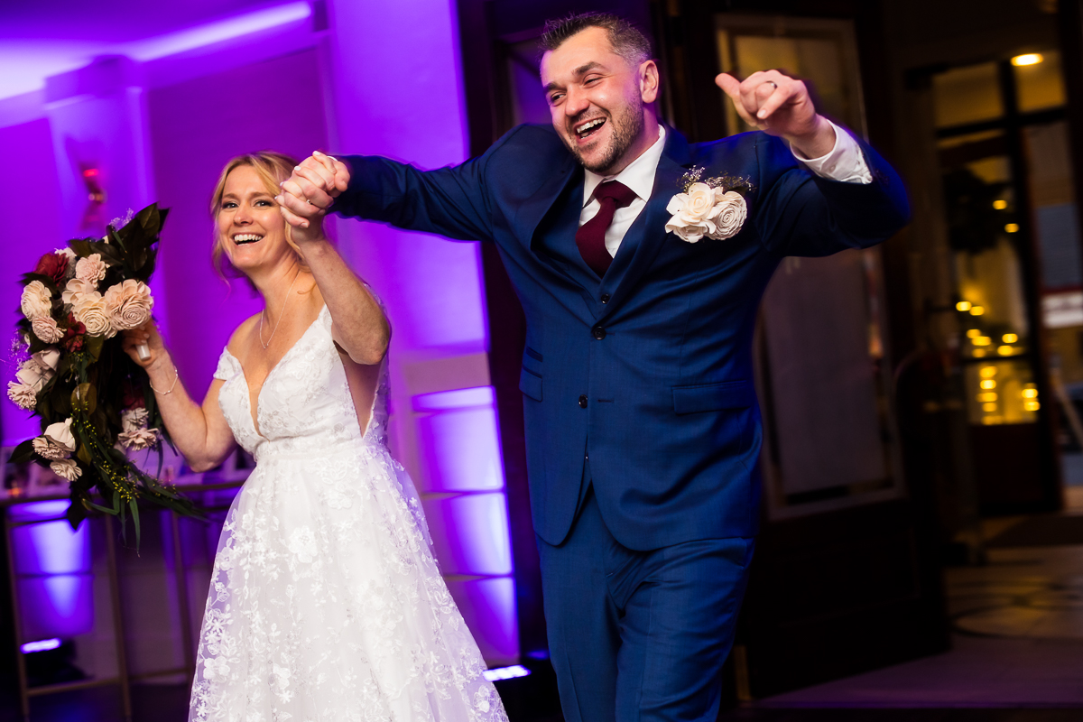 best nj wedding photographer, rhinehart photography, captures this fun entrance of the bride and groom as they enter this vibrant, colorful, fun winter wedding reception located by the beach at the reeds in New Jersey 