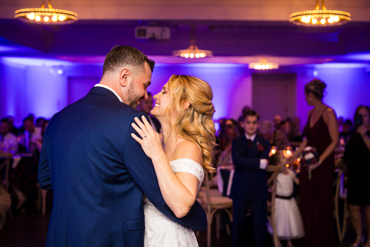 vibrant, colorful romantic image of the bride and groom as they hug one another and smile during their first dance at this Winter Reeds Stone Harbor Wedding reception 