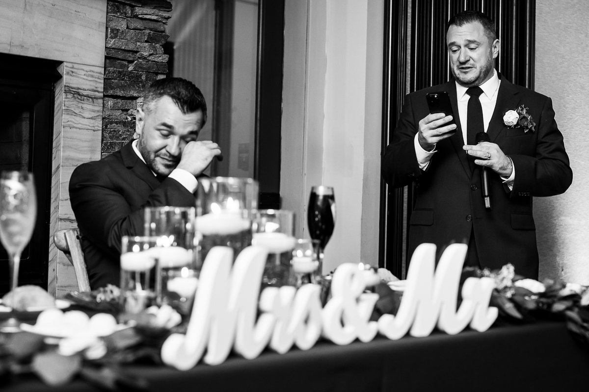 emotional, candid moment of the best man giving his speech while the groom wipes tears away captured by stone harbor wedding photographer, rhinehart photography 