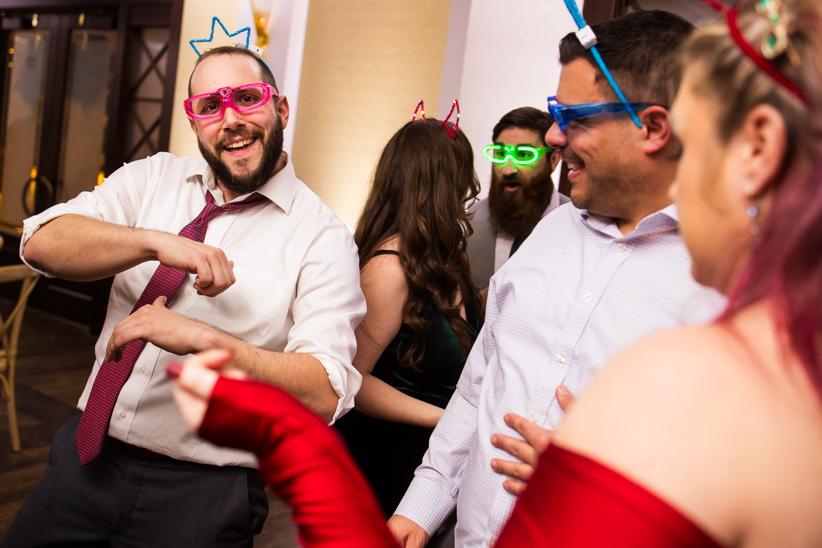 this fun Winter Reeds Stone Harbor Wedding reception features guests dancing together while wearing fun headbands and light up glasses at this kid friendly wedding reception at the reeds by the beach in New Jersey 