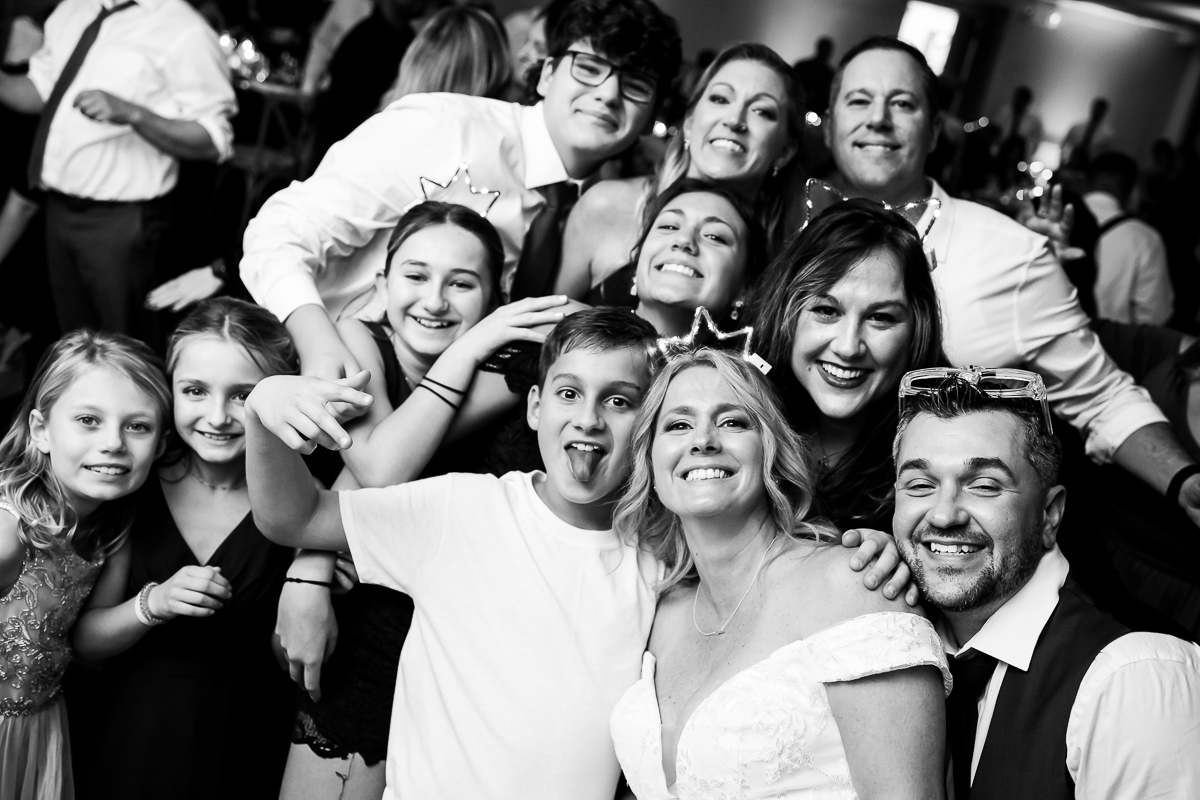 best family wedding photographer, rhinehart photography, captures this black and white image of the bride and groom and guests gathered together for a fun photo at this kid friendly Winter Reeds Stone Harbor Wedding in New Jersey 