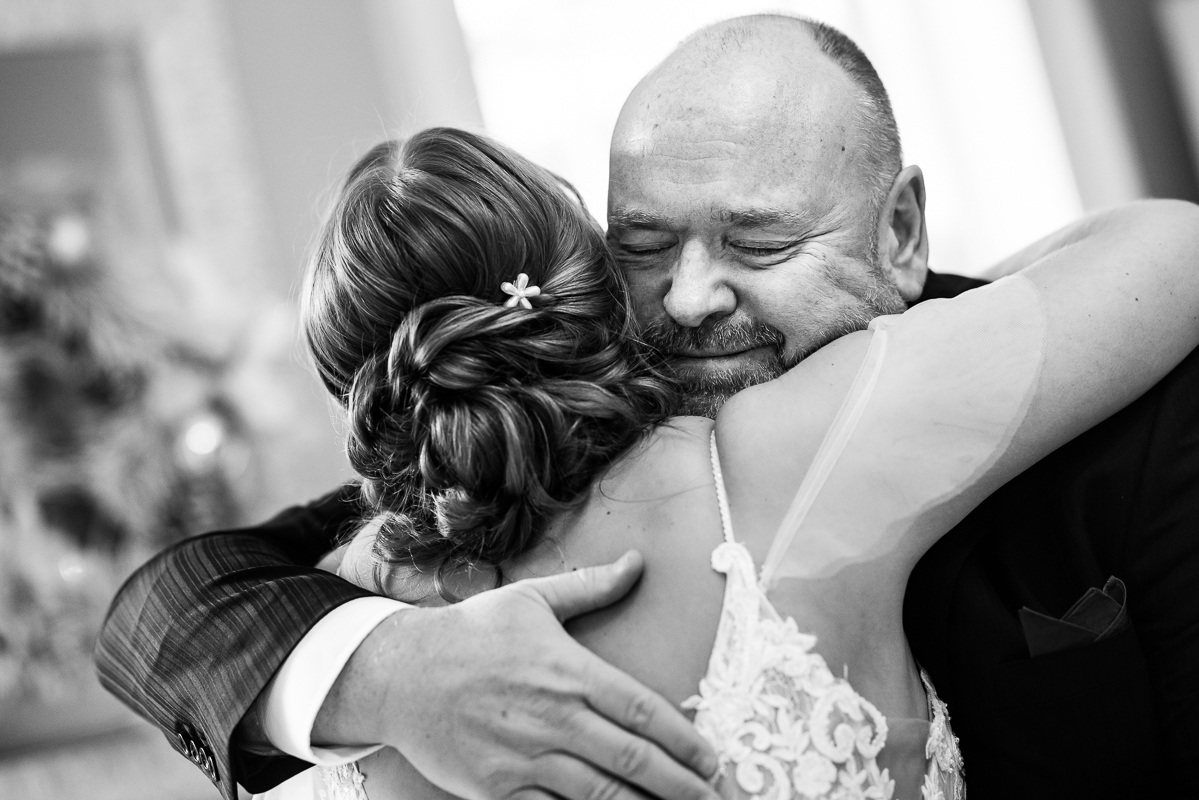 candid wedding photographer, Lisa Rhinehart, captures this authentic, emotionally moment between dad and daughter as they share a hug together after their first look before this outdoor Christmas wedding ceremony 