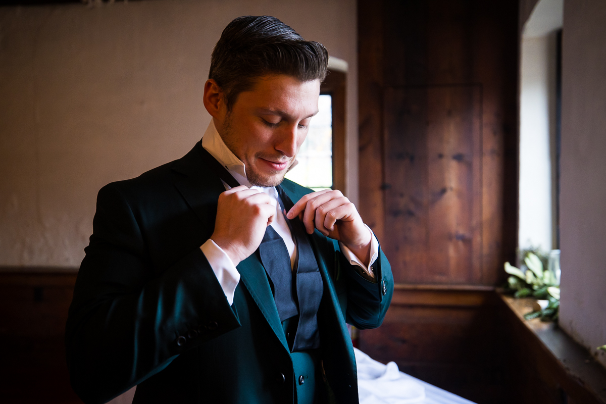 best pa wedding photographer, Lisa rhinehart, captures this candid moment of the groom as he ties his tie during wedding preparations prior to this outdoor Christmas wedding ceremony in Hallam pa 