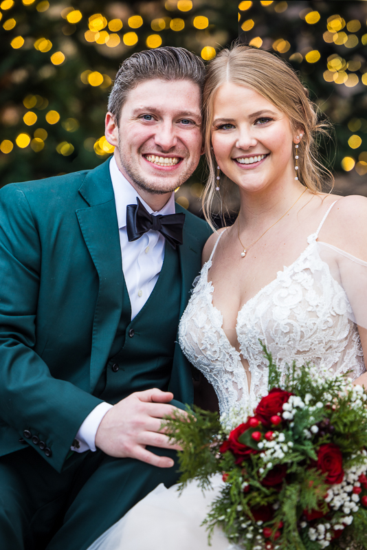 winter wedding photographer, Lisa Rhinehart, captures this traditional image of the bride and groom as they sit next to one another and smile after their outdoor winter wedding ceremony at stone mill inn 