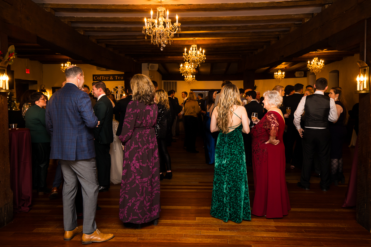 candid image of guests as they hang out and talk to one another during this stone mill inn cocktail hour after the outdoor Christmas wedding ceremony 