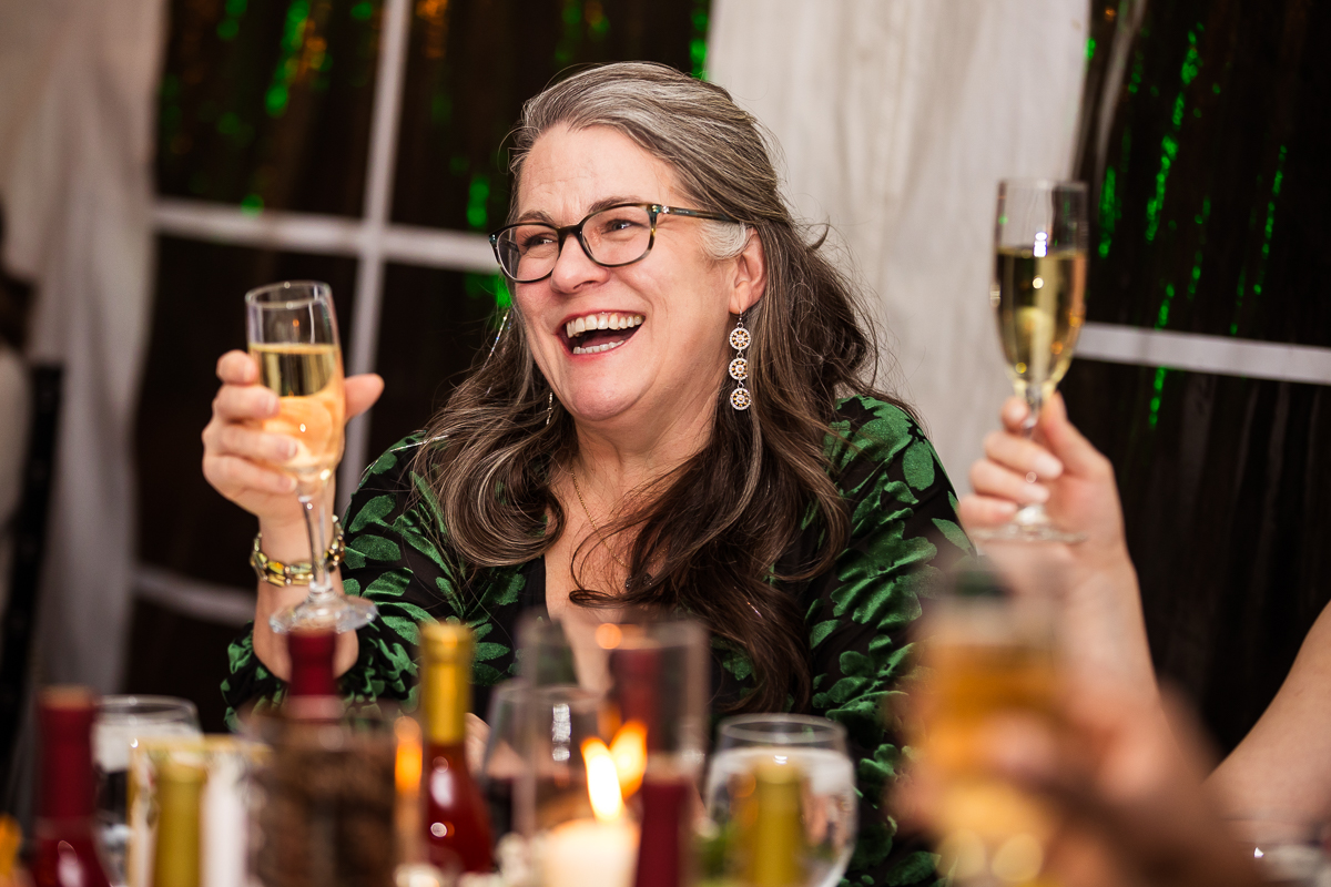 candid image of a guest as she raises her glass for a toast during the speeches at this Christmas wedding reception 