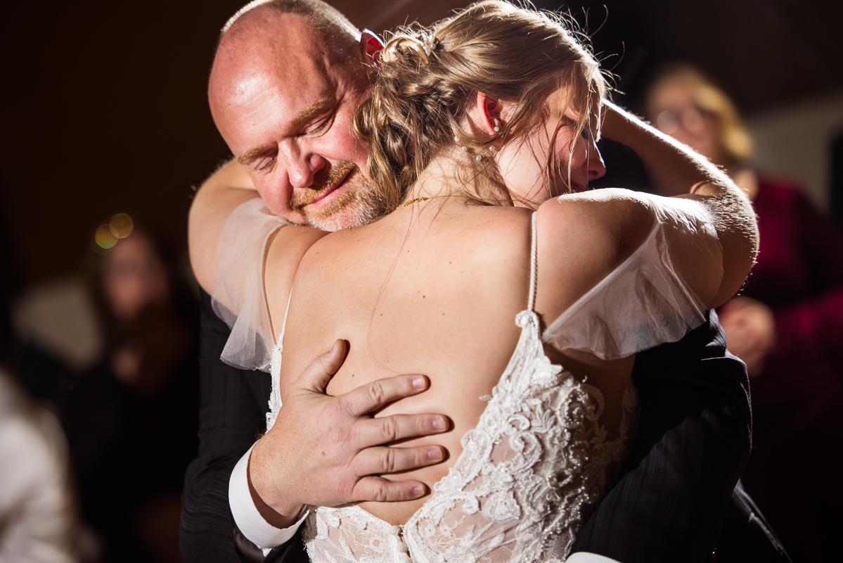 Stone Mill Inn Wedding photographer, Lisa Rhinehart, captures this emotional moment between the bride and her dad as they share a hug during the father daughter dance at this Christmas wedding reception 