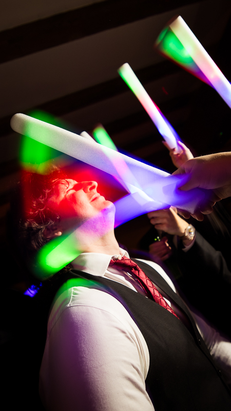 Stone Mill Inn Wedding photographer, Lisa Rhinehart, captures this vibrant image of people dancing with their colorful rainbow glow stick during this Christmas wedding reception in Hallam pa 