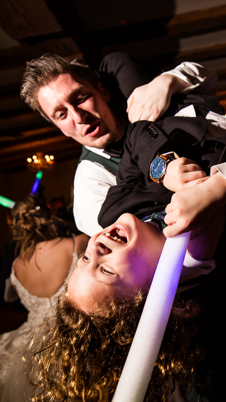 image of the groom as he dips a guest backwards while dancing with them during this winter wedding reception captured by fun wedding reception photographer, Lisa Rhinehart 