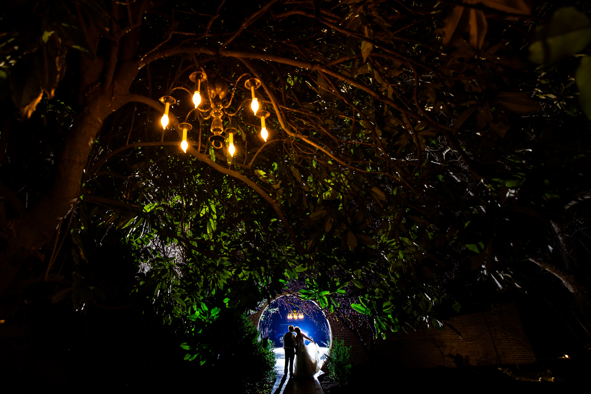 Stone Mill Inn Wedding photographer, Lisa Rhinehart, captures this creative, unique end of the night shot of the bride and groom as they stand under the moon gate and kiss after their fun Christmas winter wedding reception in Hallam pa 