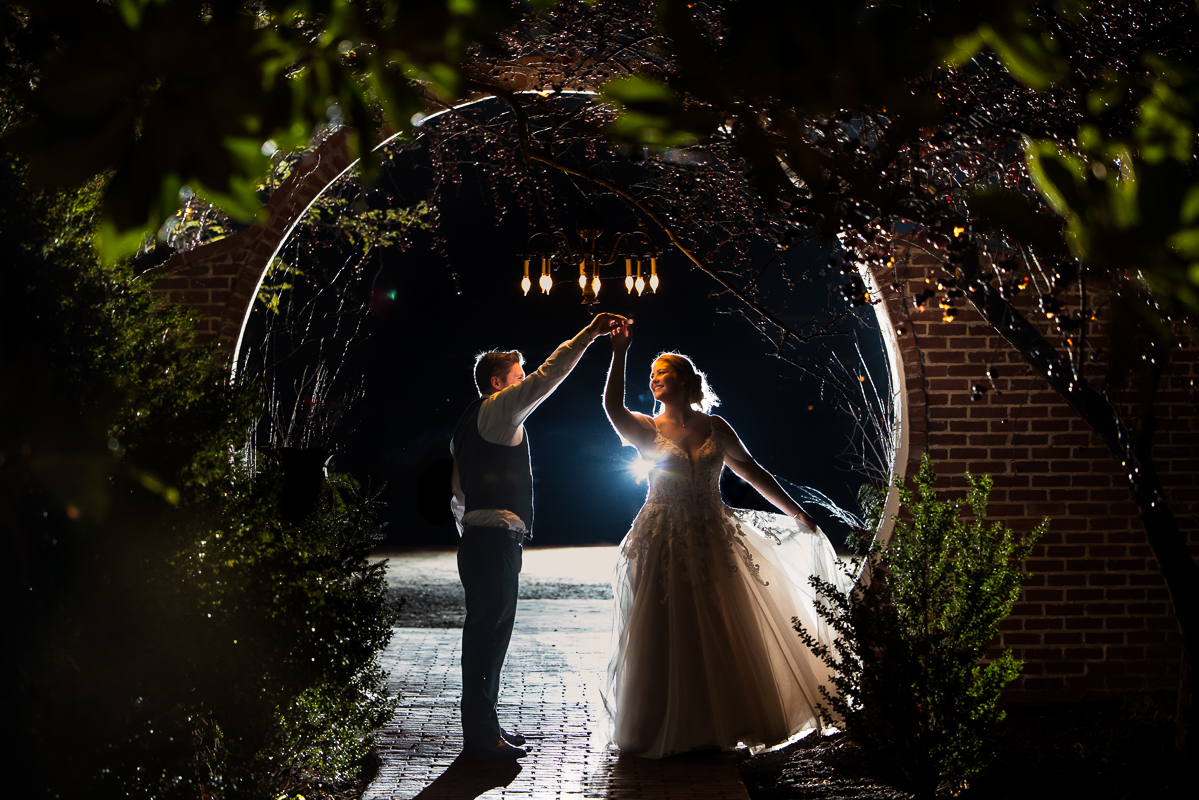 end of the night shot of the bride and groom as they stand under the moon gate and spin after their stone mill inn winter wedding reception 
