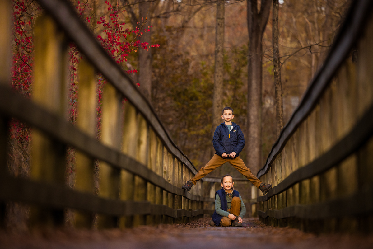 Lehigh Valley family photographer, Rhinehart Photography, captures this unique, creative image of the two brothers as they pose on the bridge during this outdoor fall family session at the wildlands conservancy in emmaus pa 
