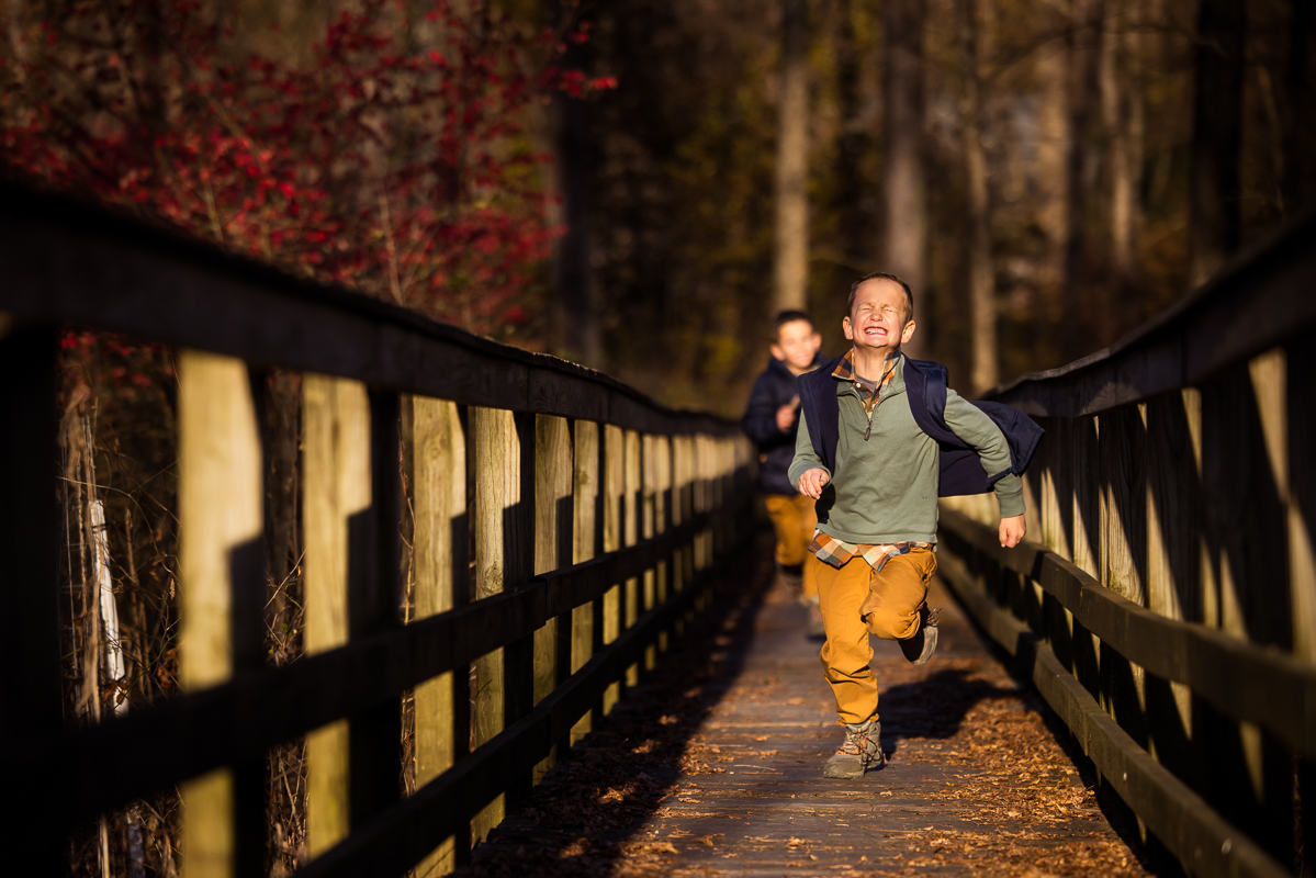 fun, candid, playful image of two kids as they run down the bridge at the wildlands conservancy in emmaus pa captured by best pa family photographer, Lisa Rhinehart 