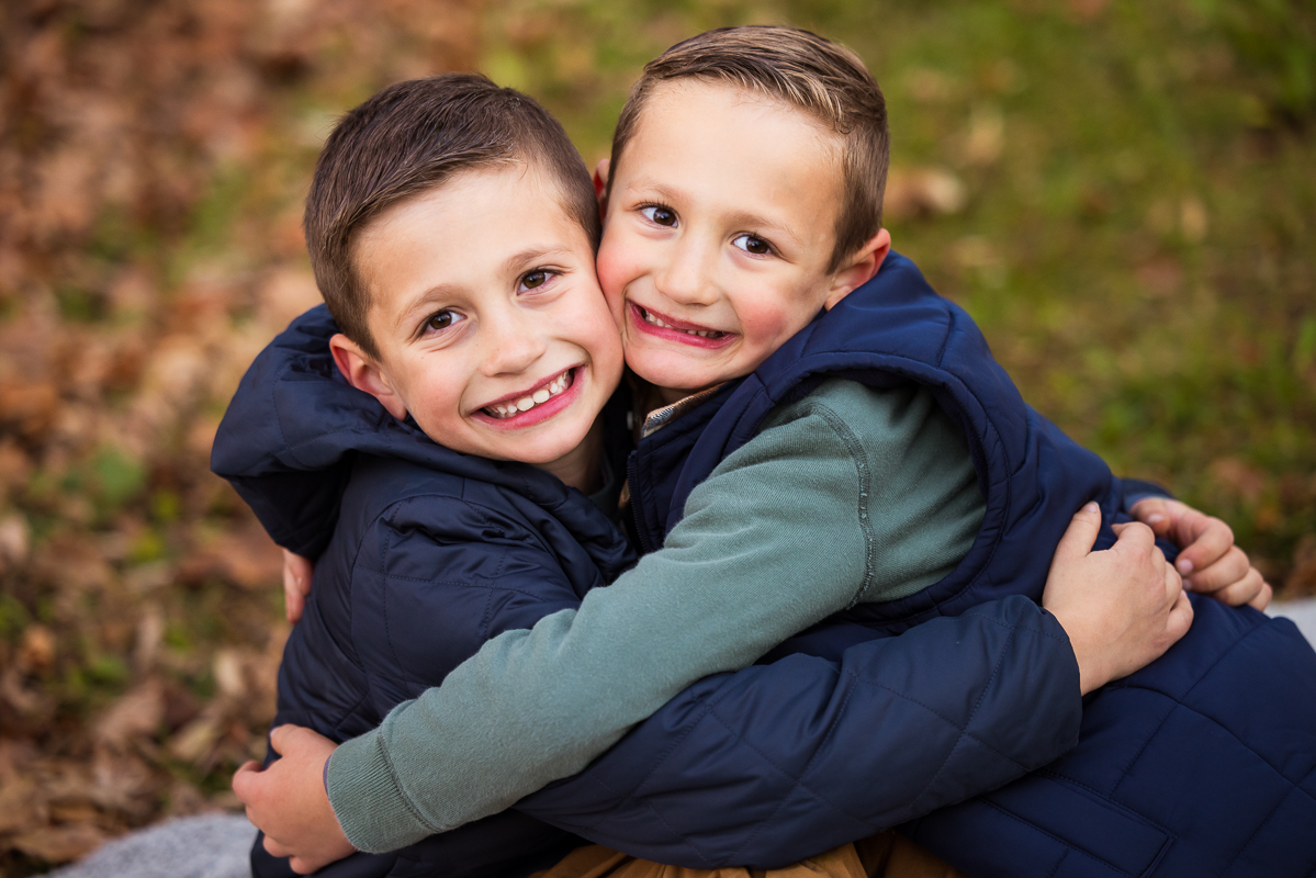 best pa family photographer, Lisa Rhinehart, captures this traditional portrait of the two brothers as they hug one another during this outdoor fall family session at the wildlands conservancy in emmaus pa 