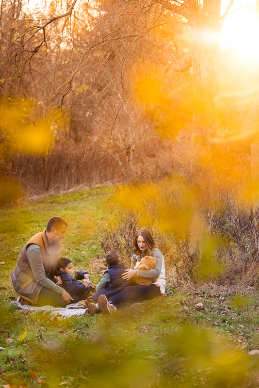creative family photographer, Lisa Rhinehart, captures this creative, candid moment of the family as they enjoy a picnic together during this vibrant, colorful outdoor fall family session at the wildlands conservancy in Lehigh Valley 