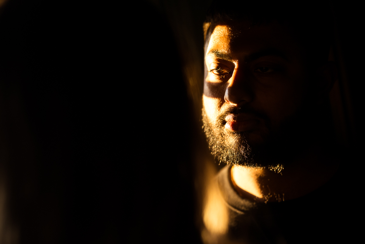 creative, unique image of the husband as he stands in the beam of sunlight highlighting half of his face inside of the willows at ashcombe mansion in central pa during this maternity session