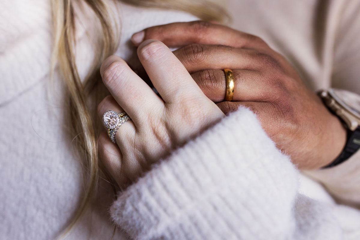 close up image of the husband and wife as they hold hands and show off their wedding bands during this cozy maternity session in central pa at the mansion 