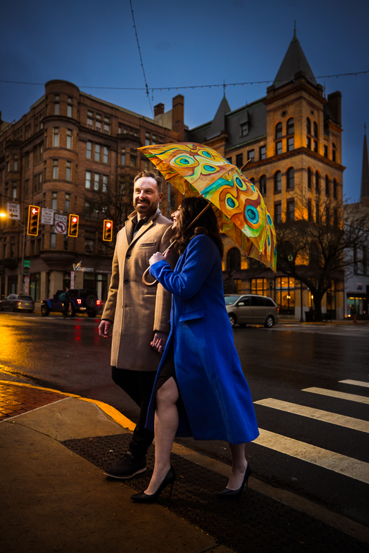Yorktowne Hotel Wedding engagement photographer, Lisa Rhinehart, captures the couple in this colorful night time shot of the couple as they walk across the road in Downtown York during their engagement session with the Rupp building in the background 
