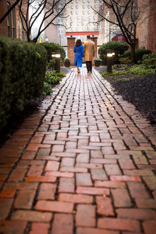 image of the couple as they walk down the red brick walkway for this outdoor winter engagement session in York pa 