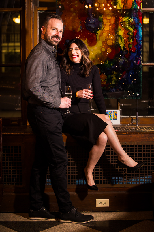 Yorktowne Hotel Wedding engagement photographer, Lisa Rhinehart, captures this image of the couple as they share a drink together inside of the Yorktowne hotel with vibrant, colorful artwork behind them in York pa 