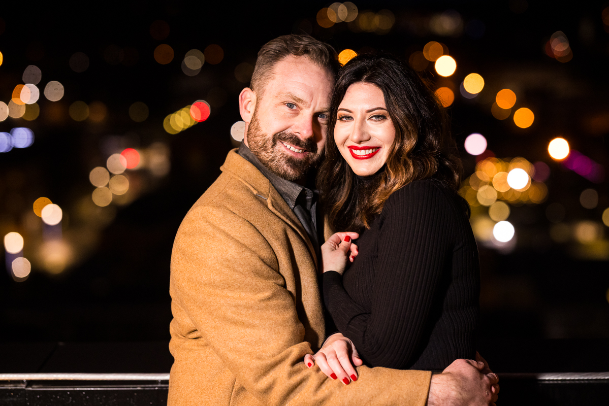 traditional portrait of the bride and groom as they embrace one another and smile at the camera during this outdoor winter engagement session 